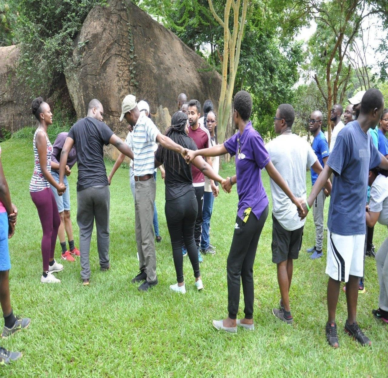 Team members holding hands in a circle during an outdoor exercise