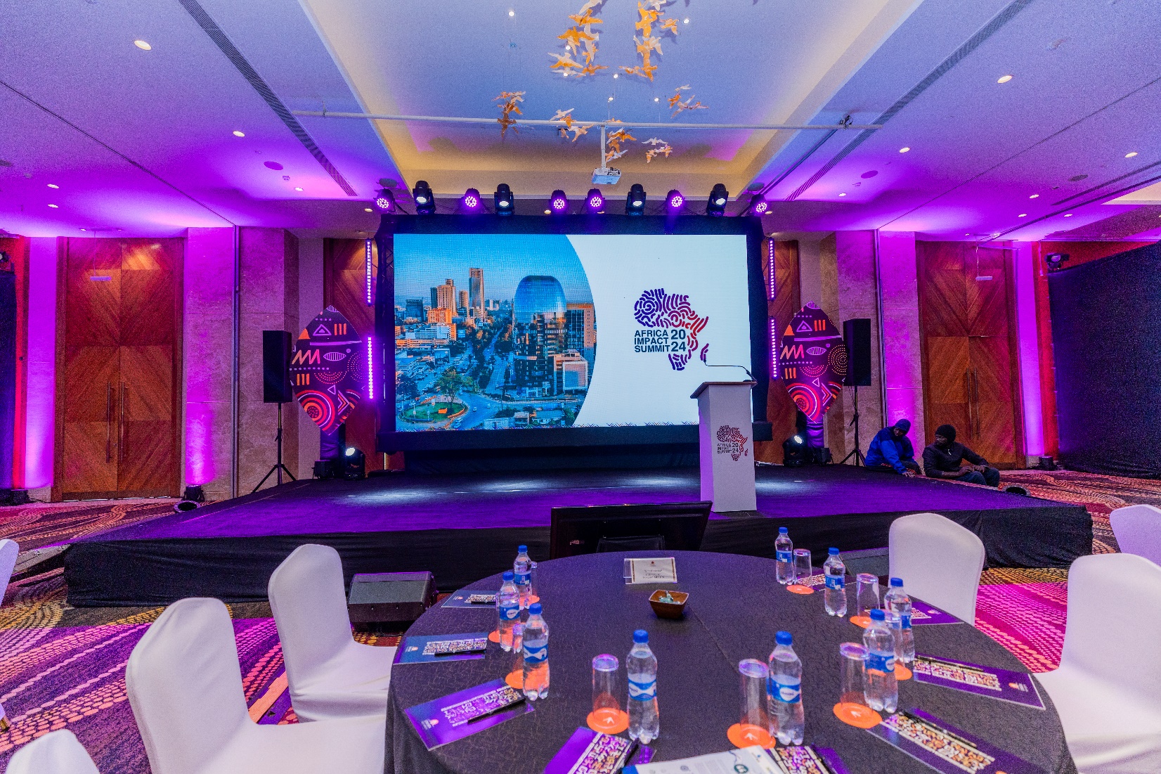 Main stage and banquet tables lit in purple at the Africa Impact Summit