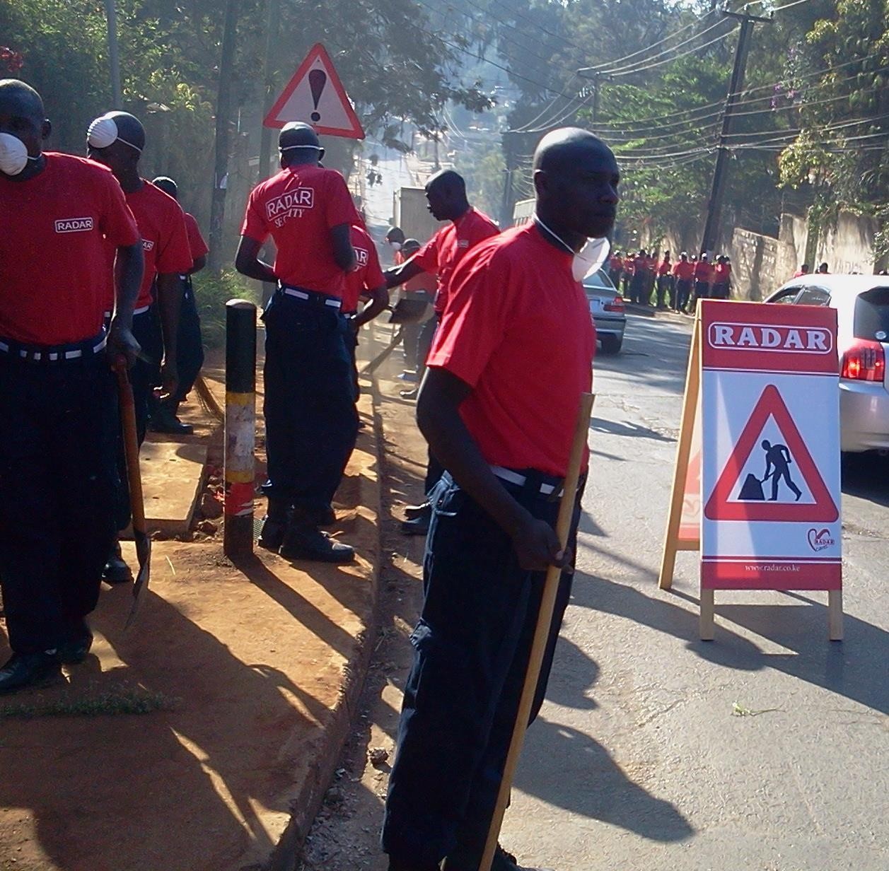 Volunteers in branded shirts clearing a roadside during a CSR activity